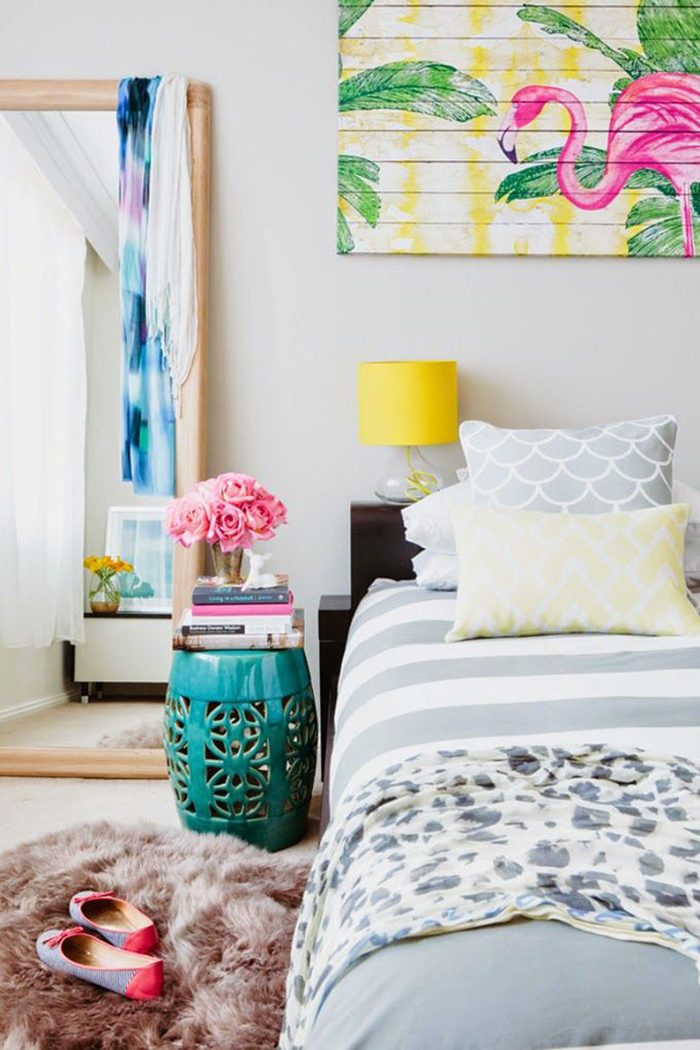 Bedroom with a flamingo picture above the bed and flowers next to it