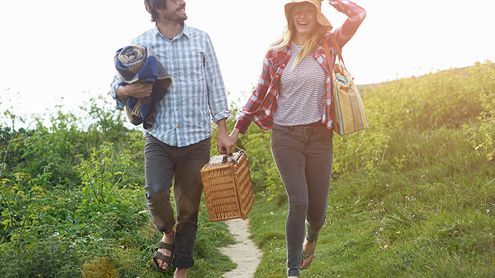 A couple holding hands and walking through a meadow