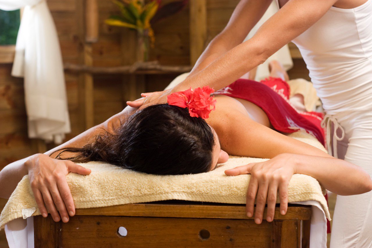 Woman massaging another woman with flower in her hairs in Costa Rica