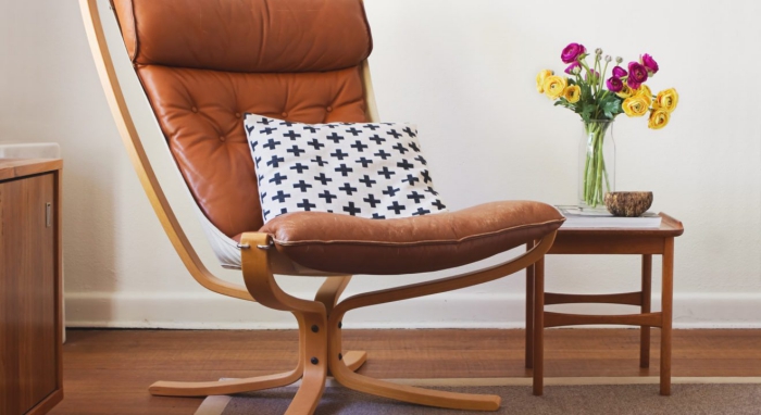 Mid Century Danish lounge designs reading chair with a cushion on it and flowers on a small table