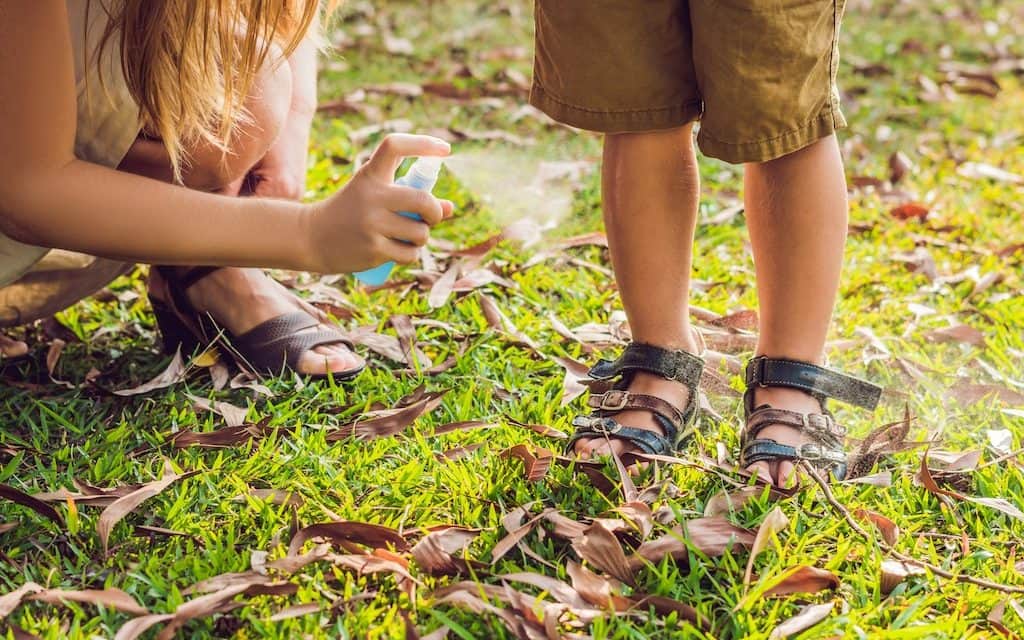 Mother applying natural repellent against insects on her son's legs