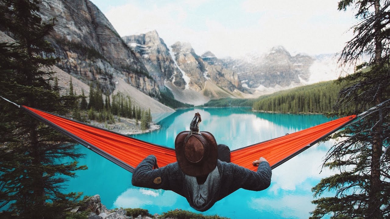 Man with a hat enjoying in his hammock with a view on a clear sea