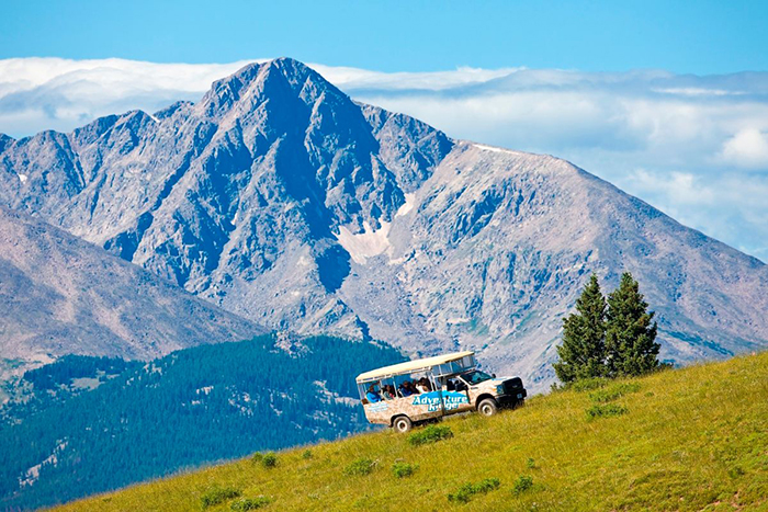 A tourist van on a meadow surrounded by high hills