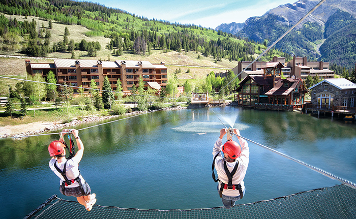Two person on a zip line over a lake in Vail, Colorado
