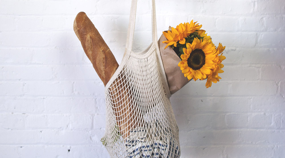 Reusable groceries bag with bread and flowers inside