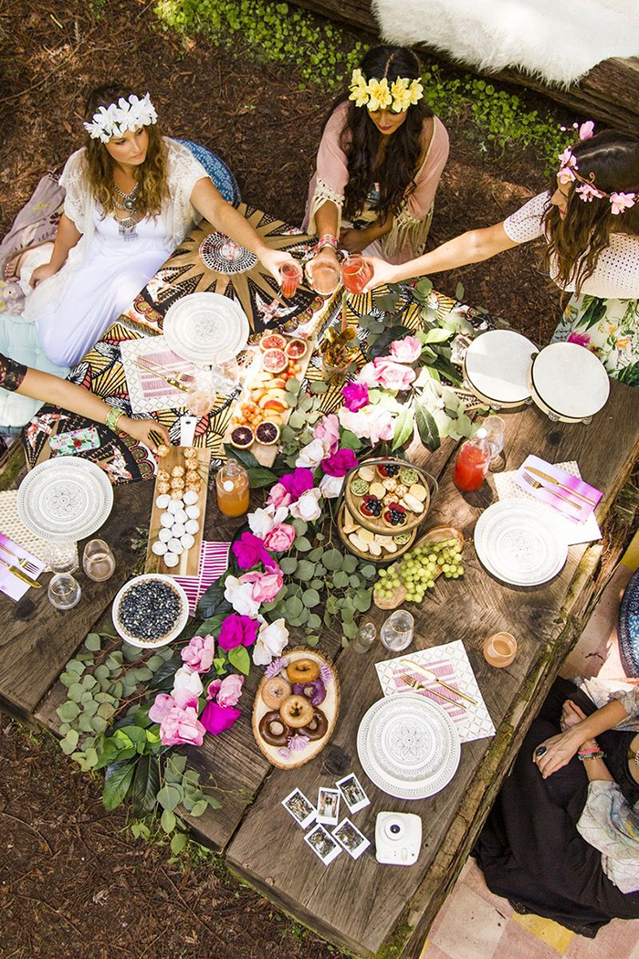 Girls with dresses and floral wreaths making a toast on a nice decorated table with food