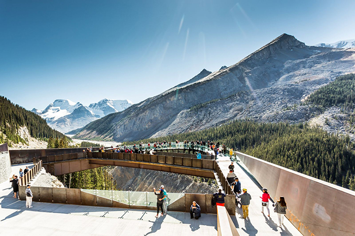 Tourists exploring Banff while walking on a bridge with a view on the mountains