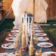 Summer party table decorated with candles in bottles and decorated jars instead of glasses