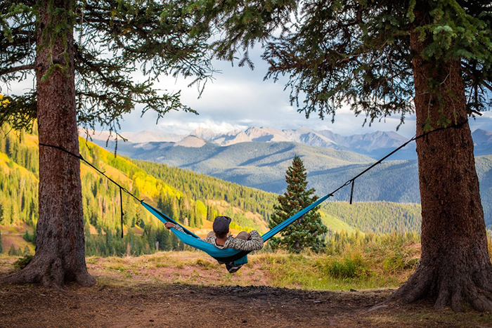 A person on a hammock with a view on meadows and mountains