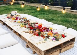 Short wooden table in garden full of food