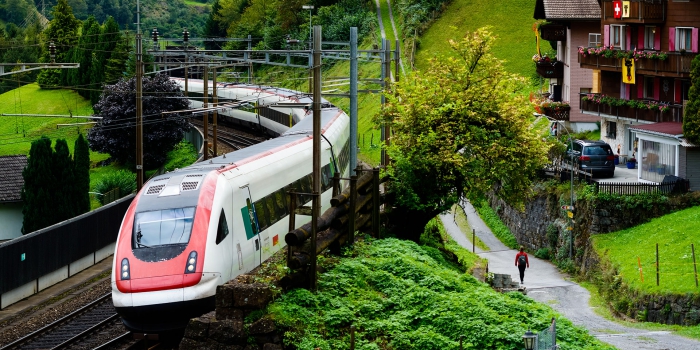 white and red train passing by some nice houses