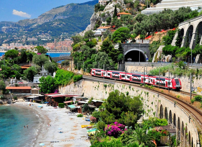 white and red train passing by the beach in Italy