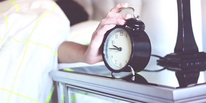 hand snoozing an alarm clock