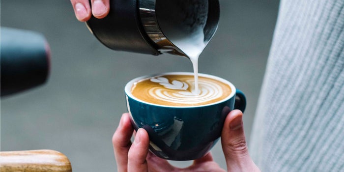 hand pouring cream into coffee