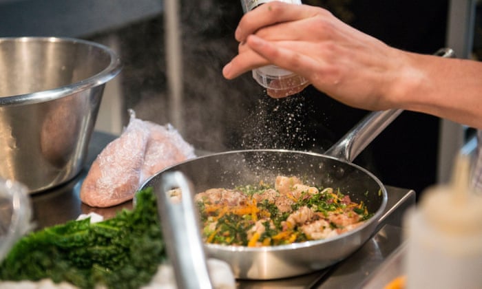 hand adding spices to a meal