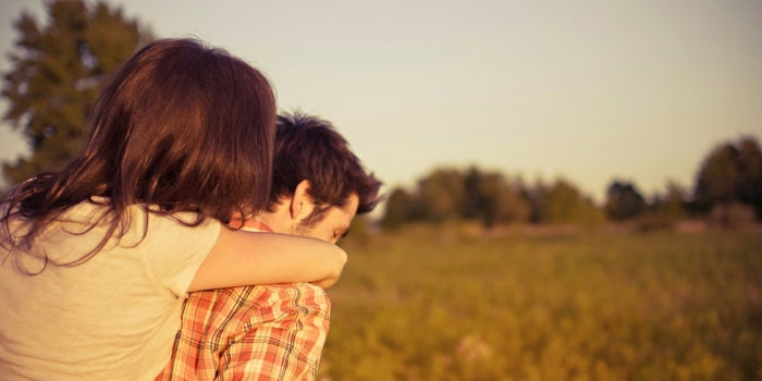 man carrying a woman through fields on his back