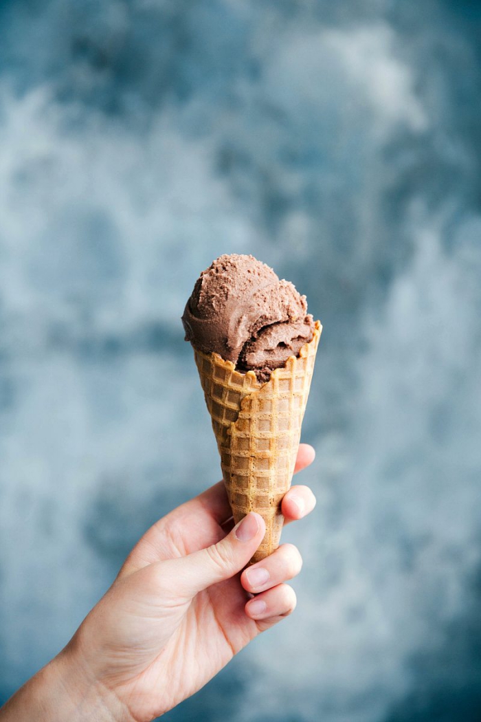 A hand holding a cone with chocolate gelato