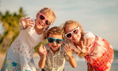 Three children waving and smiling at camera
