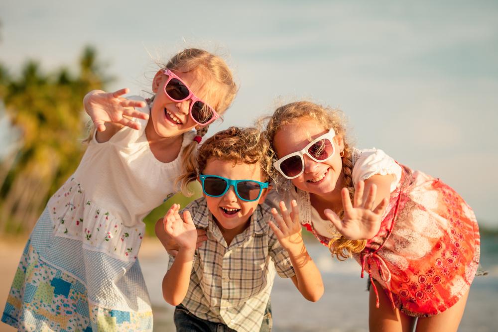 Three children waving and smiling at camera