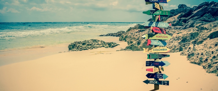  beach with a sign showing different directions