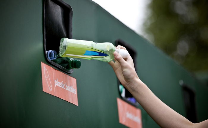 Hand throwing plastic bottle into a containter