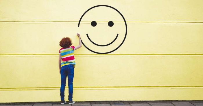 Woman drawing a smiley face on bright yellow wall