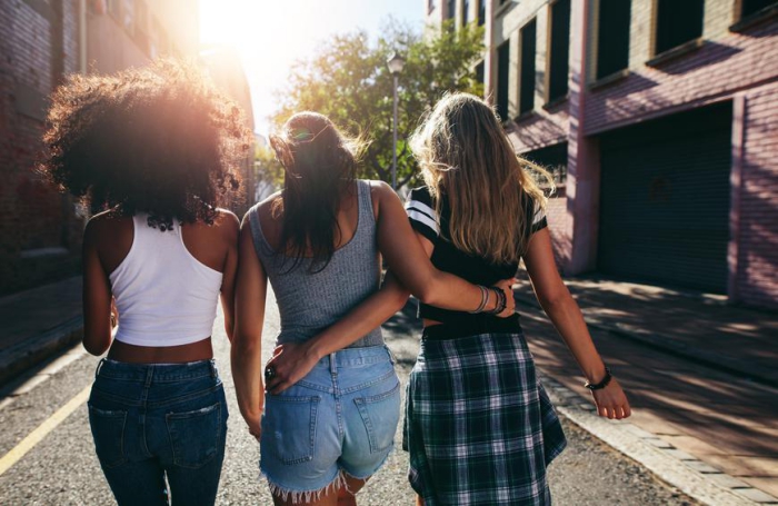 Three women friends walking hugged