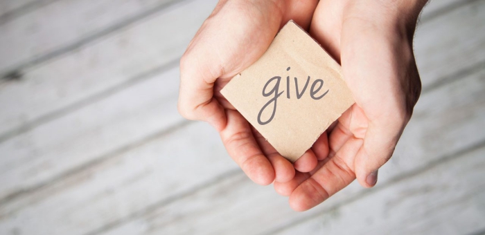 Two hands holding a sign that says give