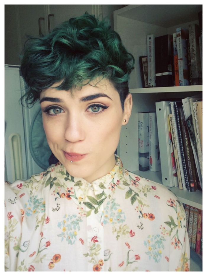 Young woman at home with light skin and eyes curly green pixie hairstyle