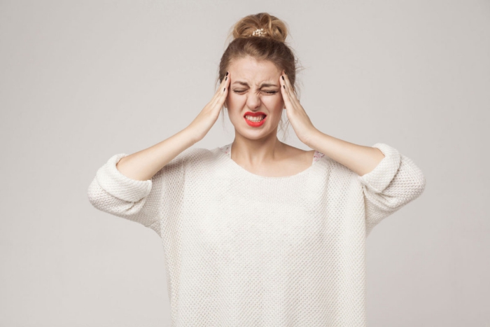 Woman with her hands on her head having migraine 