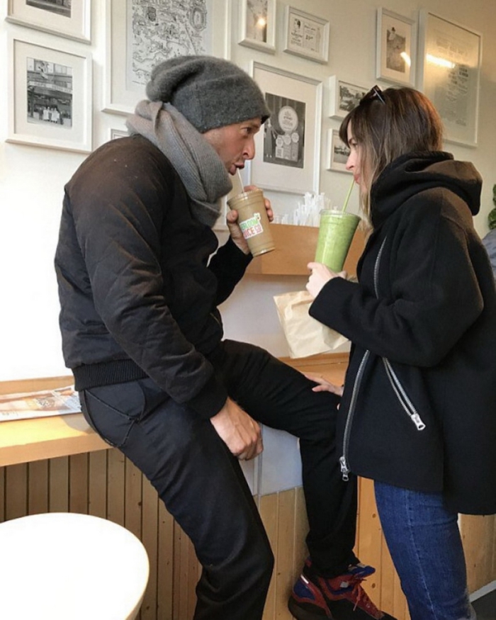 Dakota Johnson and Chris Martin drinking coffee in a bar dressed casual