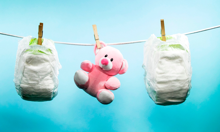 two diapers and pink teddy bear hanging 