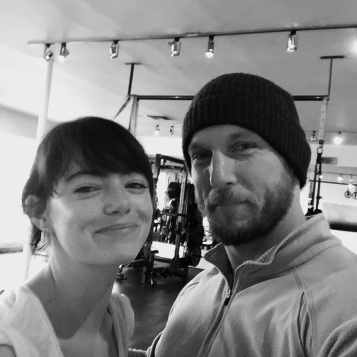 Emma Stone smiling at the camera with fitness instructor at the gym