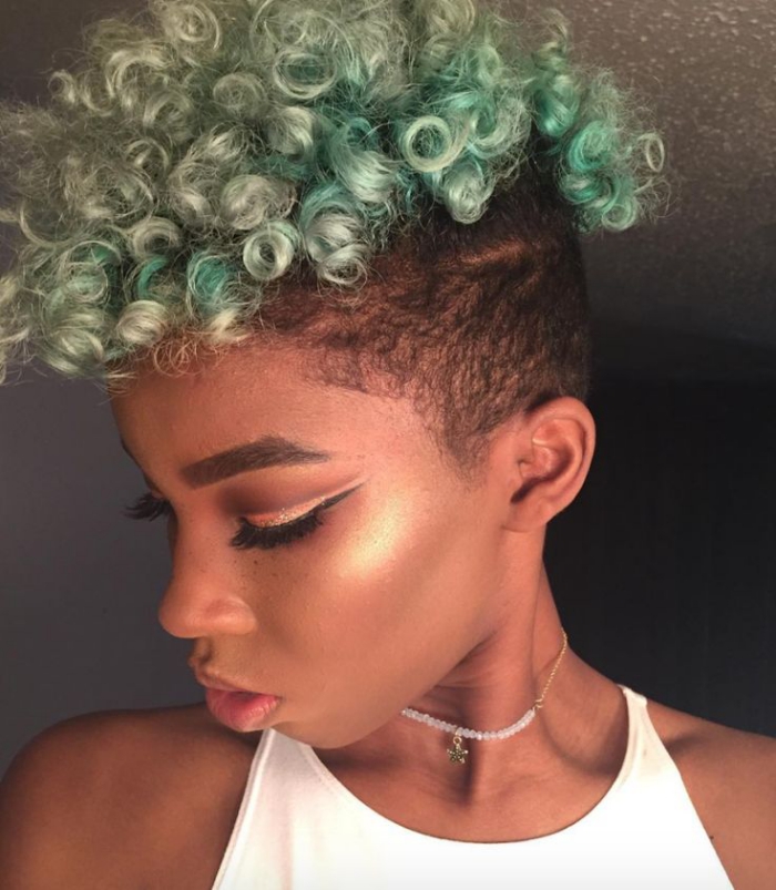 woman looking down tight curl afro green pixie
