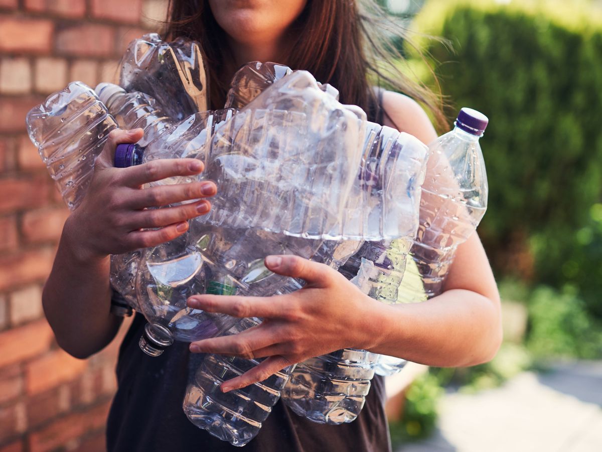 woman holding bunch of empty plastic bottles