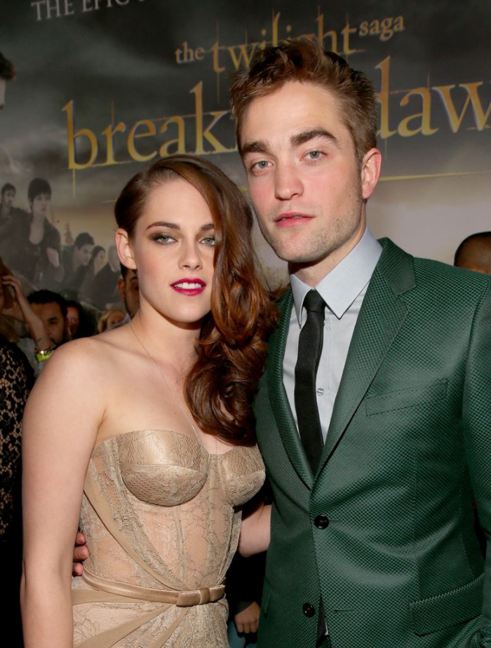 Kristen Stewart and Robert Pattison posing in front of a poster