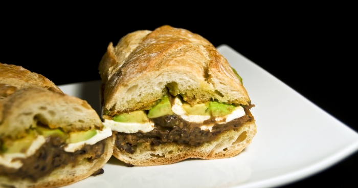 Two Mexican lonches on a white plate with black background