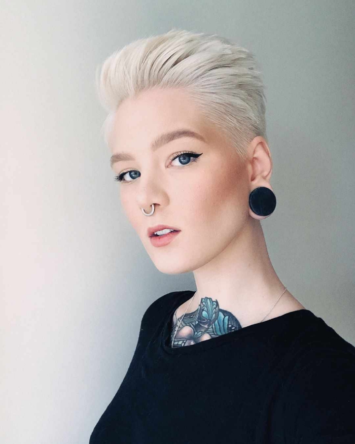 woman with white hair nose piercing and tattoo dressed in black on white background