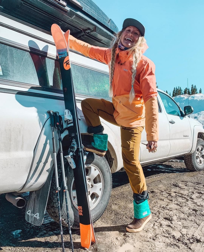 Rachel Pohl smiling leaning on a truck with a pair of skis