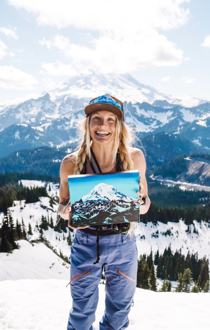 Rachel Pohl in the mountains showing her painting