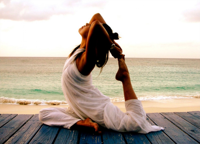 Spiritual practices woman dressed in white doing yoga on the beach