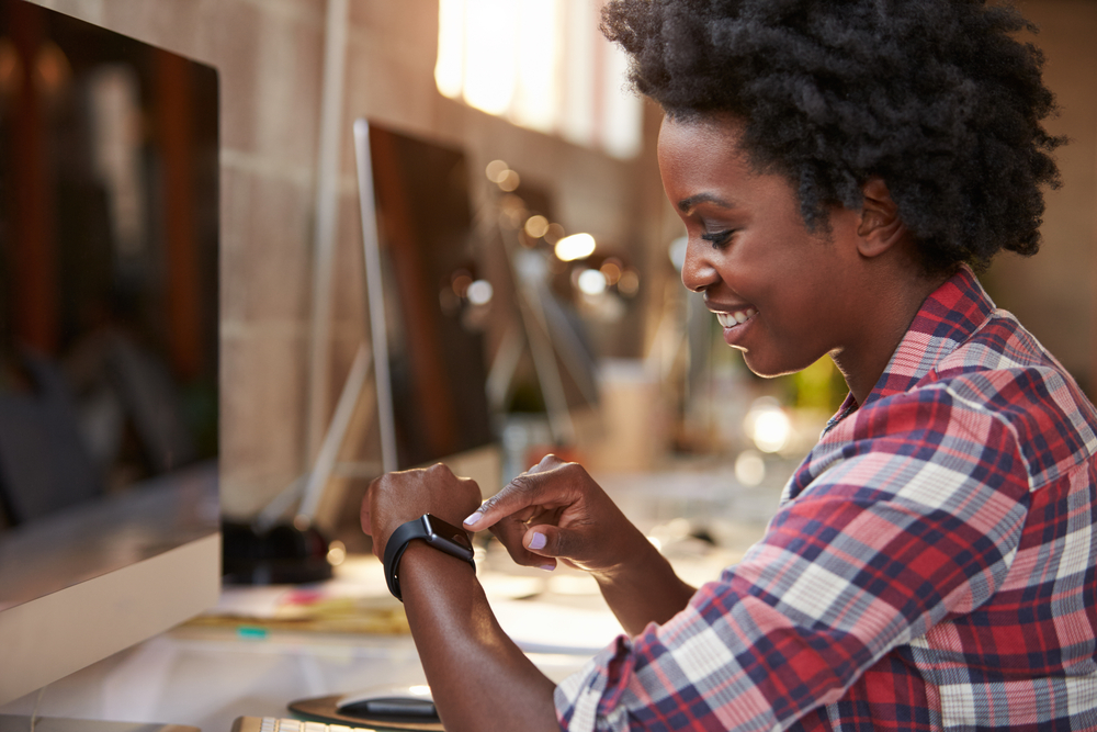 Students' gadgets Woman looking at her smart watch sitting in front of big screen