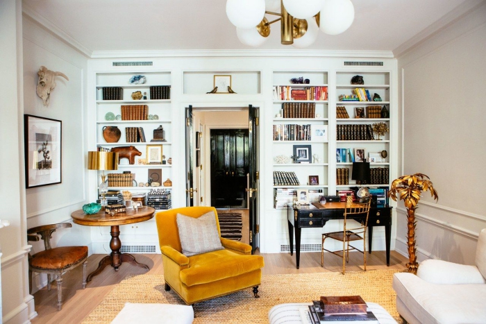 Modern living area with library, desk and reading armchair in mustard yellow