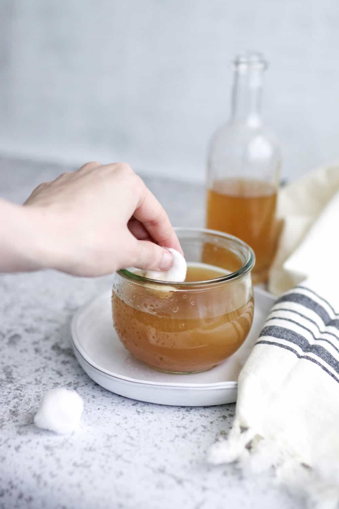 woman hand cotton pad apple cider vinegar in a jar