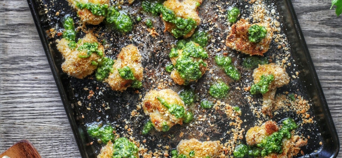 baked cauliflower bites with pesto in a black baking tin