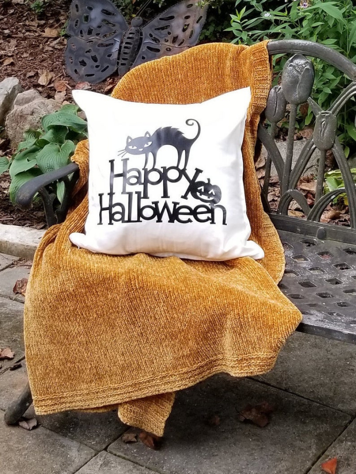 Halloween home decor cushion cover with black cat on a bench with a blanket