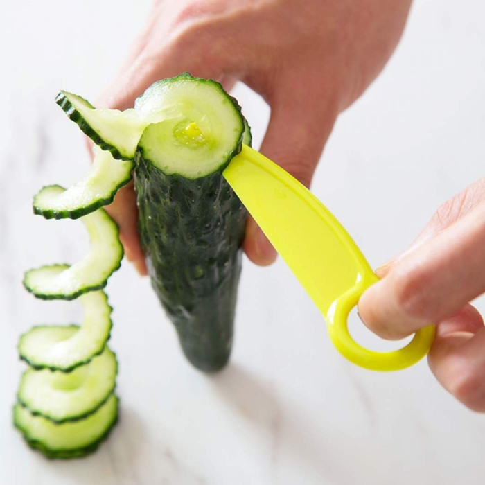 hand cutting cucumber in a spiral with yellow cutting tool