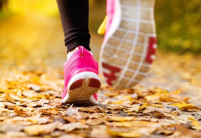 Woman jogging in a park fallen leaves pink running shoes