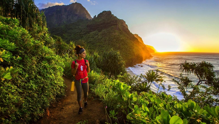 Things to do in Hawaii woman hiking along green NaPali Coast