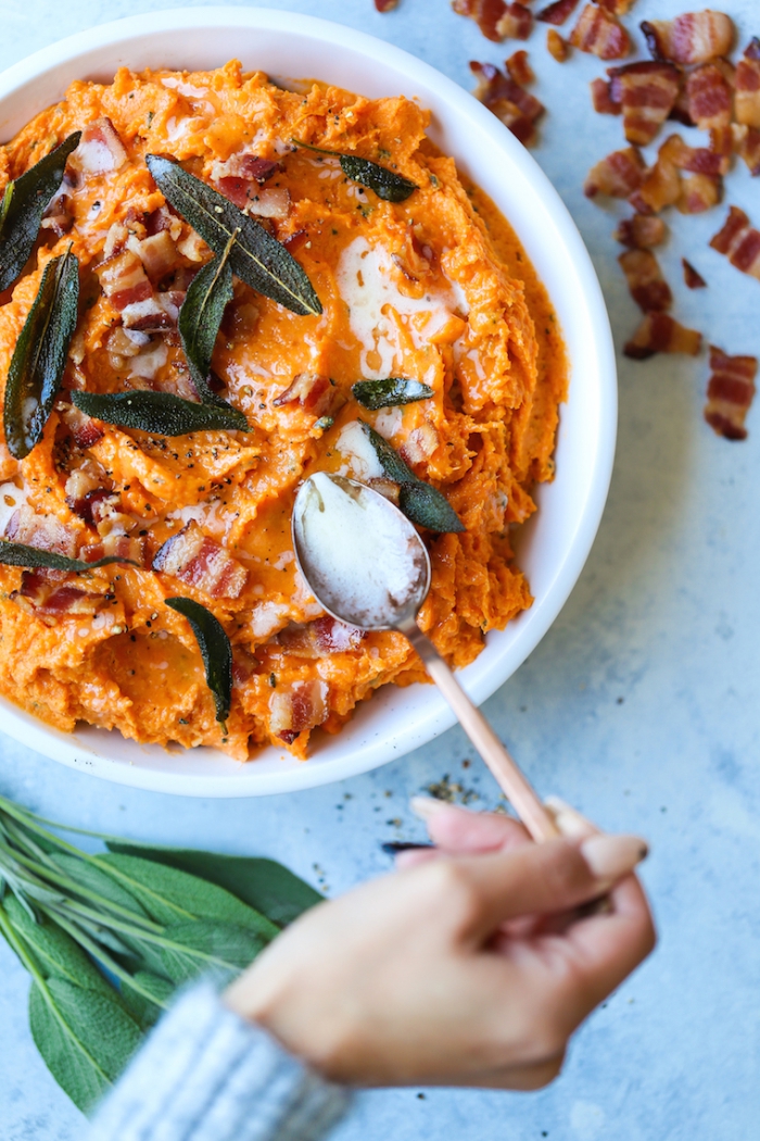 hand adding milk with a spoon close up mashed sweet potatoes with spices and bacon